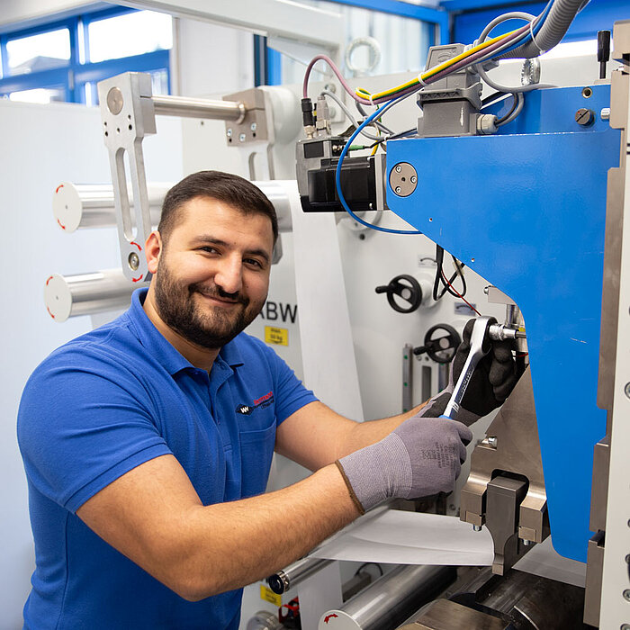 Herrmann Ultraschall employee adjusts a welding machine with a ratchet